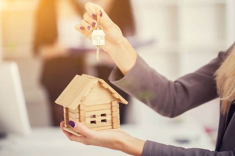 手拿样板房的销售人员是将房子钥匙交给买家-客户从房屋销售部收到钥匙-在卖家和买家之间交付房子钥匙-房屋销售概念形象