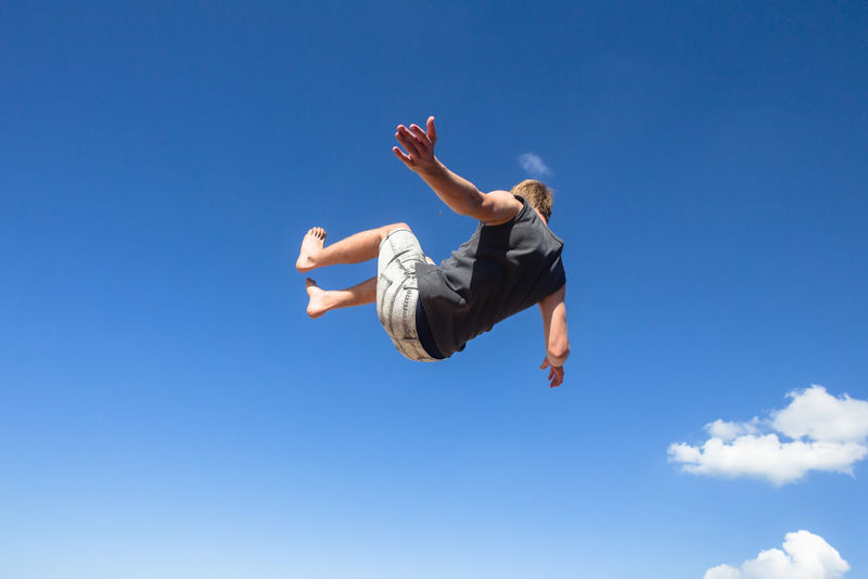 男孩jumping somersault跑酷的蓝色的天空