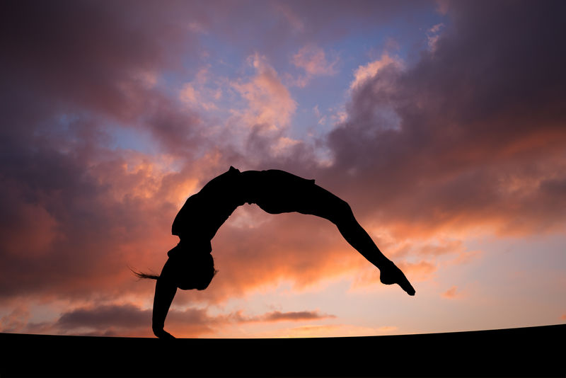 落日天空中女体操运动员的后发力