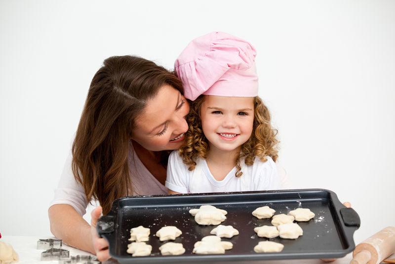 快乐的小女孩和她妈妈拿着一盘饼干