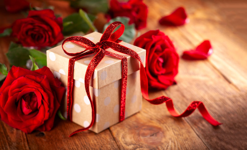 带红丝带蝴蝶结和红玫瑰的礼品盒