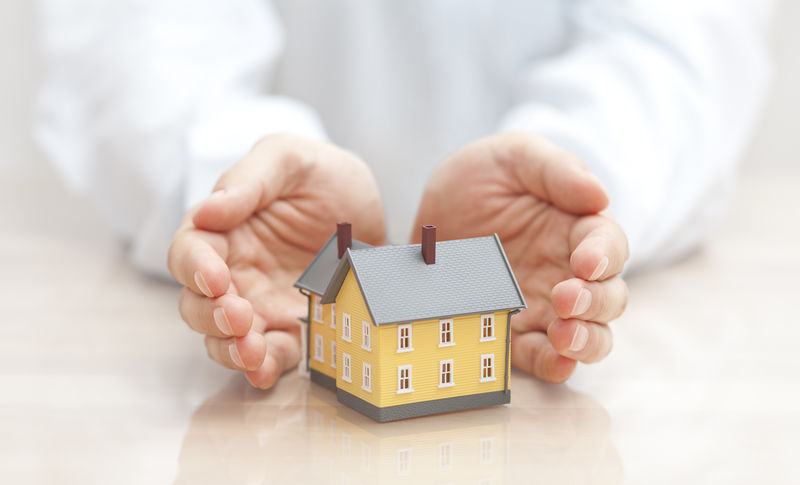 家庭保险概念-小黄房子-用手盖着