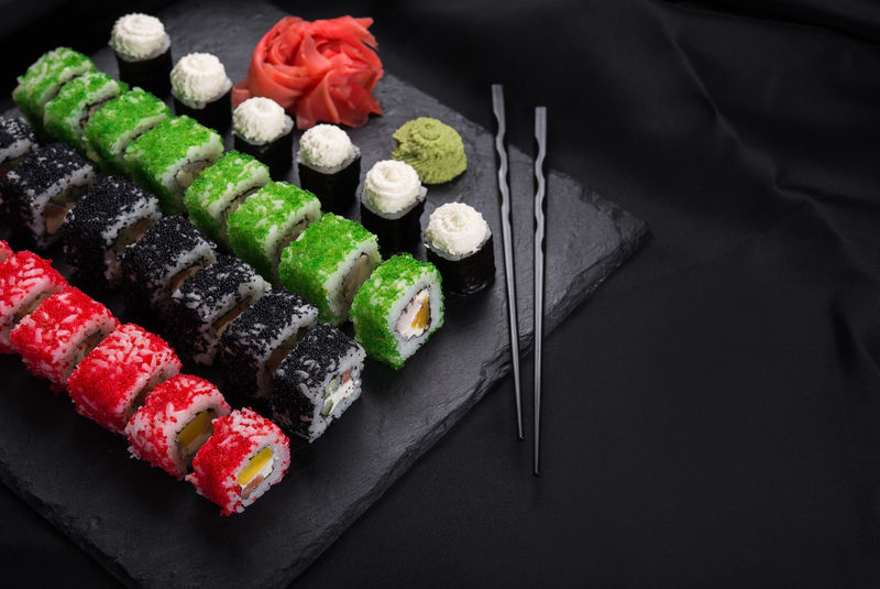 寿司卷-背景是黑石板上的芥末和姜