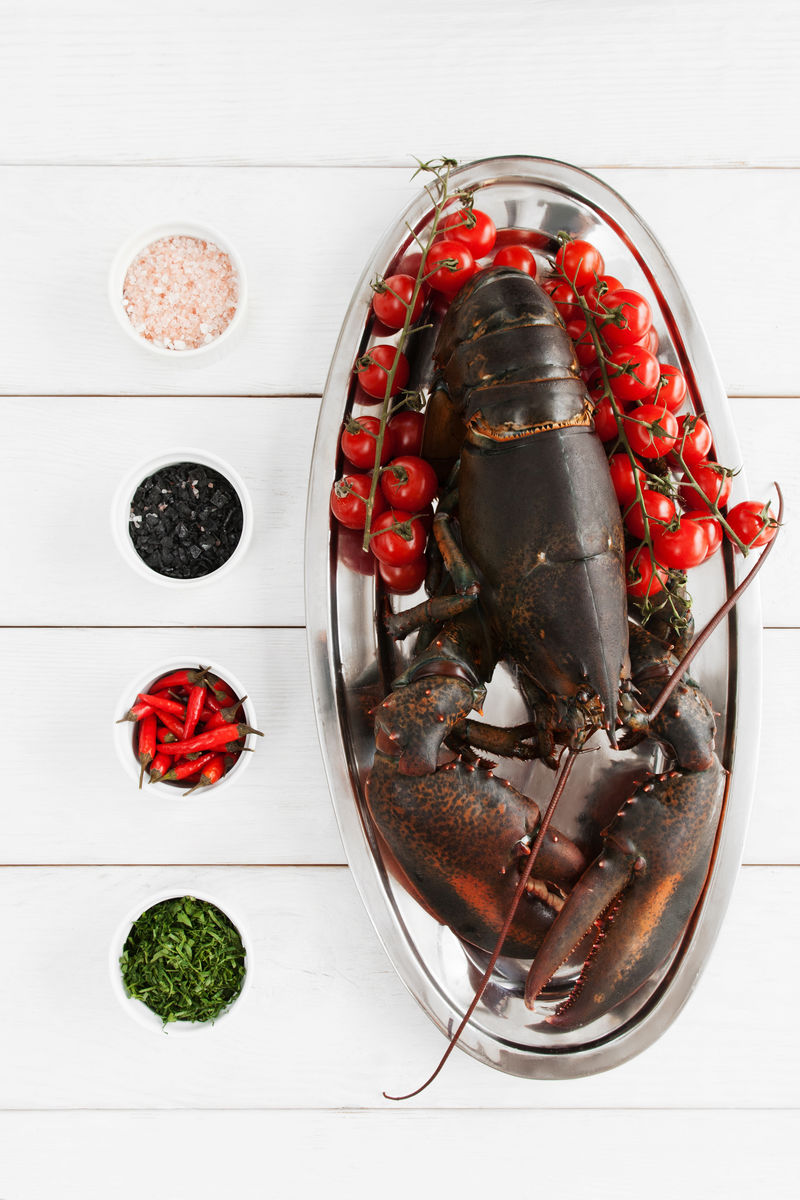 大龙虾在烹制前放在盘子里平放在桌上原配方海鲜地中海菜白木底生小龙虾