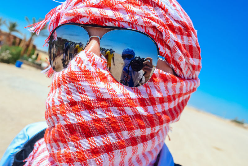 在撒哈拉沙漠一名男子戴着凯菲耶反光太阳镜镜头中有摄影师的反光