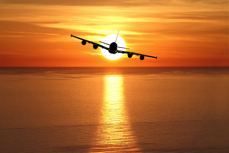 美丽的日落和飞机在海上-旅游理念
