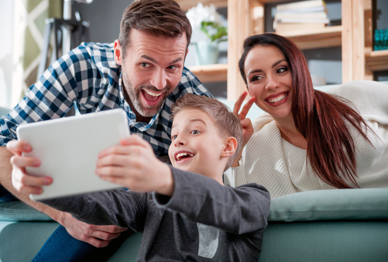 快乐家庭在家沙发上用平板电脑拍自拍照片