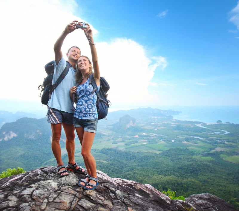 一对背着背包的快乐夫妻在山顶拍下了自己的照片