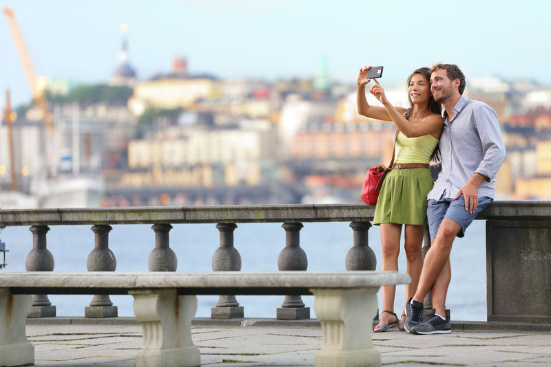 欧洲旅行-斯德哥尔摩的浪漫情侣游客在瑞典斯托克霍尔姆斯市政厅拍摄自拍照片-享受天际美景和河流的乐趣