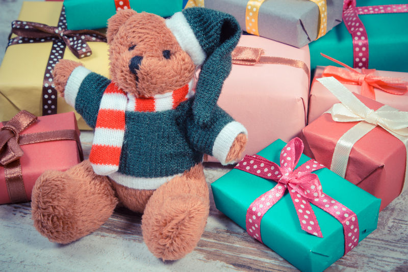 老式照片-毛绒玩具熊和一堆彩色包装的圣诞礼物-生日礼物-情人节礼物或其他节日礼物放在旧的木制白色桌子上