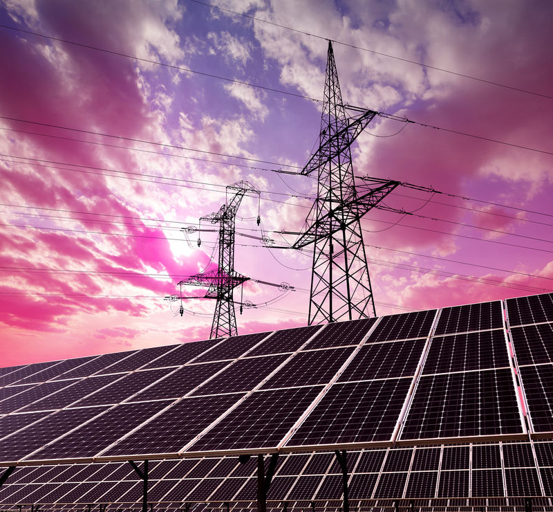 日落时带有电塔的太阳能电池板清洁能源概念