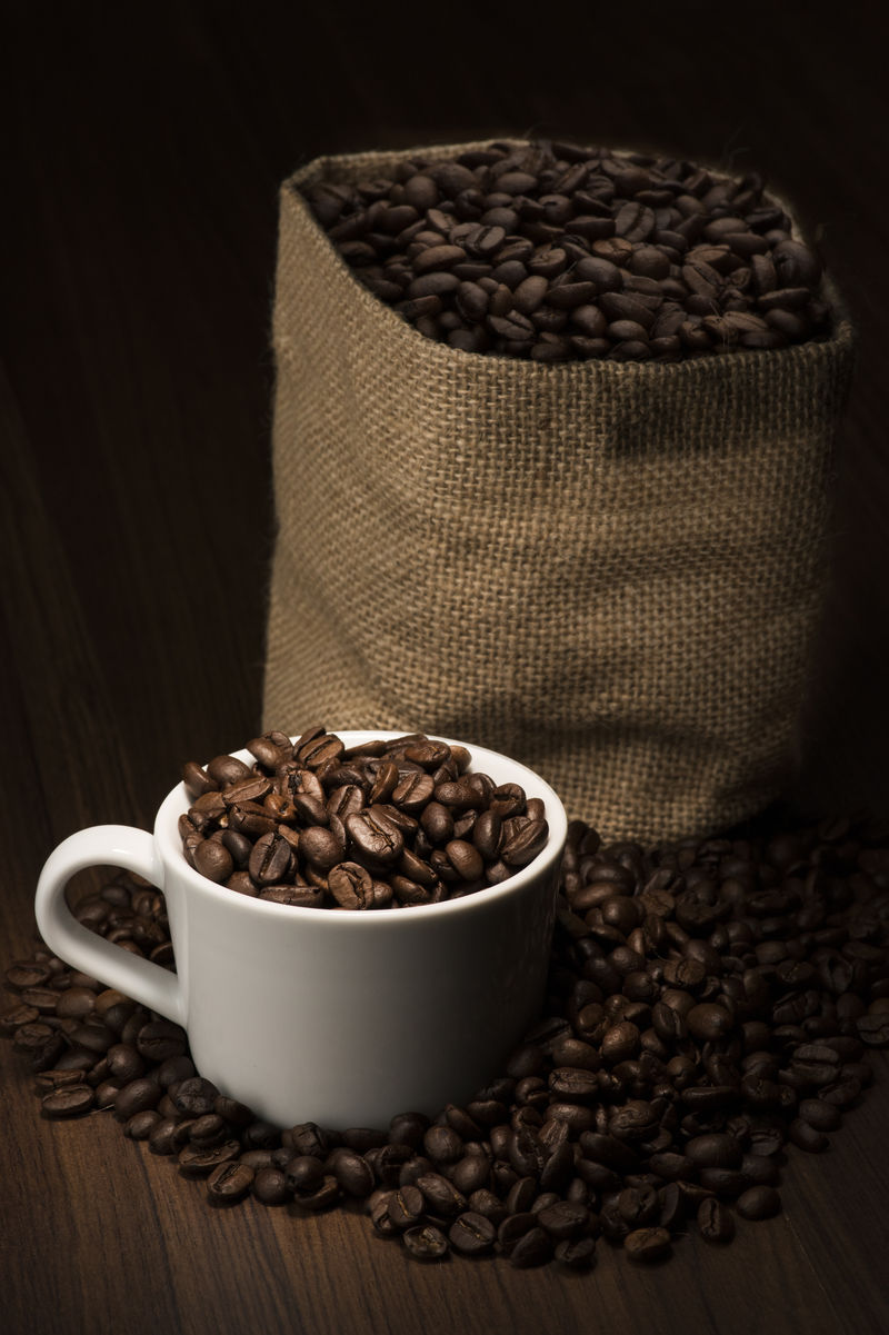 咖啡豆放在咖啡杯中咖啡豆袋放在背景中
