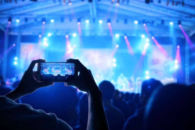 观众群使用智能手机享受现场音乐音乐会的力量