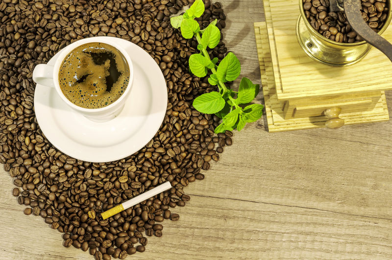 木桌上的一杯新鲜咖啡咖啡豆咖啡研磨机雪茄和薄荷茶花