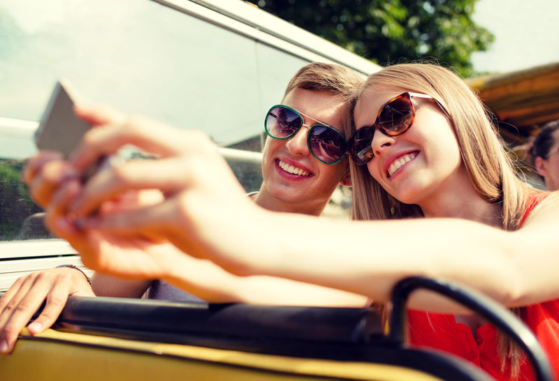 旅行度假科技夏季和人的概念-带智能手机的微笑情侣乘坐旅游巴士和自拍