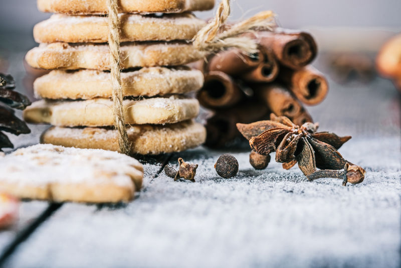 用圣诞装饰品和香料把曲奇饼捆在木桌上的特写镜头选择性聚焦