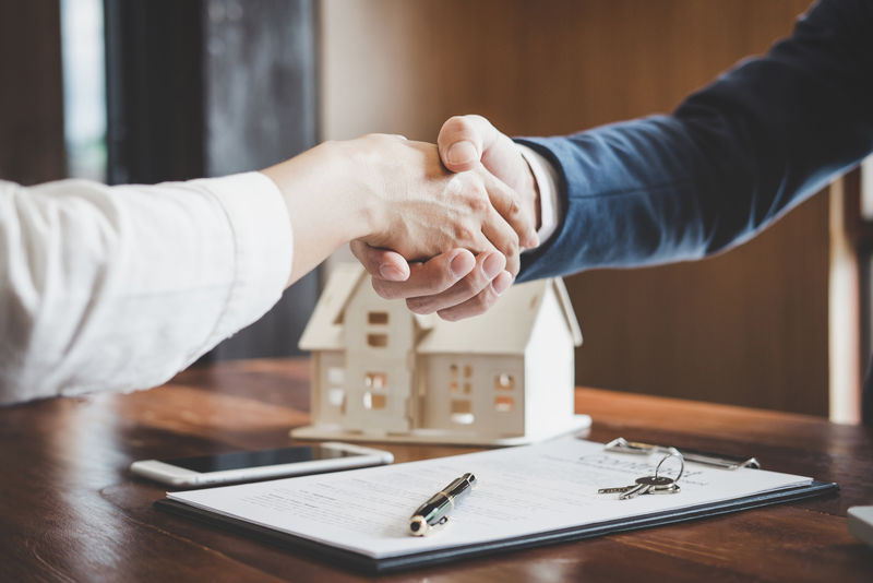 房地产经纪人和客户握手庆祝完成合同后-关于住房保险和投资贷款-握手和成功的交易