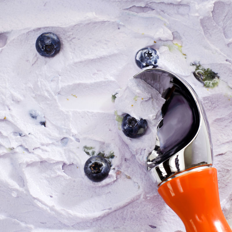 红色柄勺特写镜头提供蓝莓冰淇淋上面撒上新鲜蓝莓