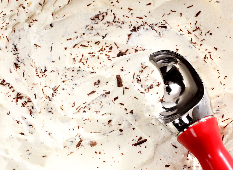 勺的特写镜头：在白色香草冰淇淋上撒上巧克力屑