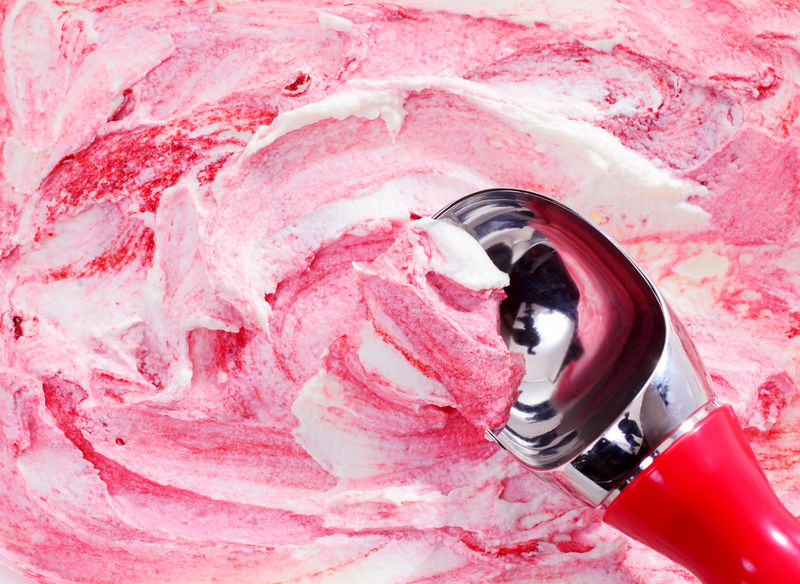 从大角度看勺子铲起一份粉红色浆果漩涡冰淇淋