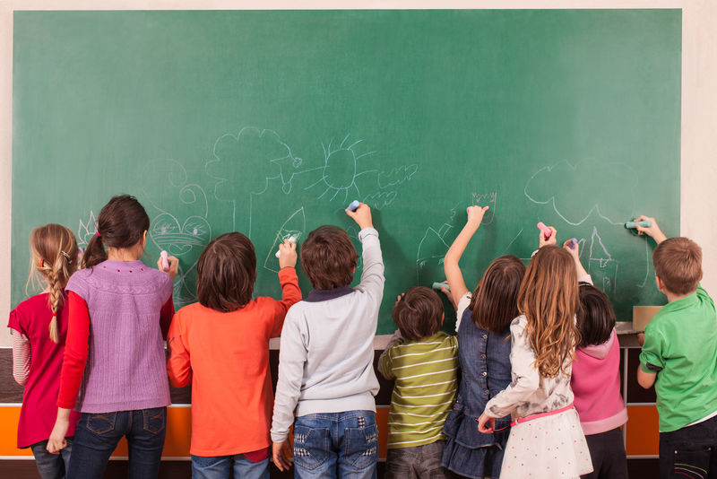 九个孩子用粉笔在学校黑板上画画
