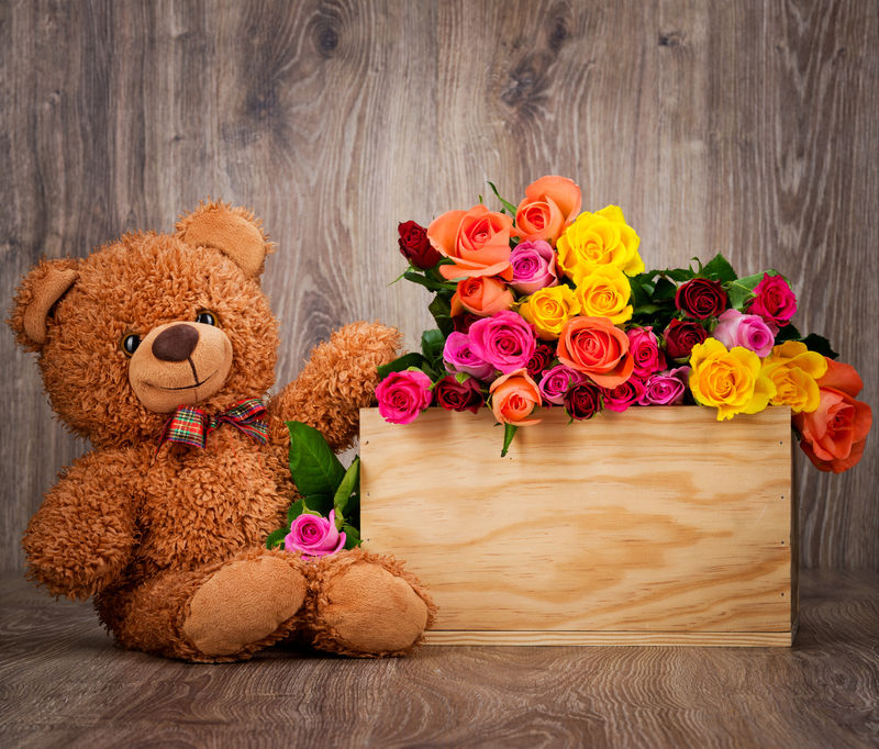 盒子里的玫瑰和木制的泰迪熊