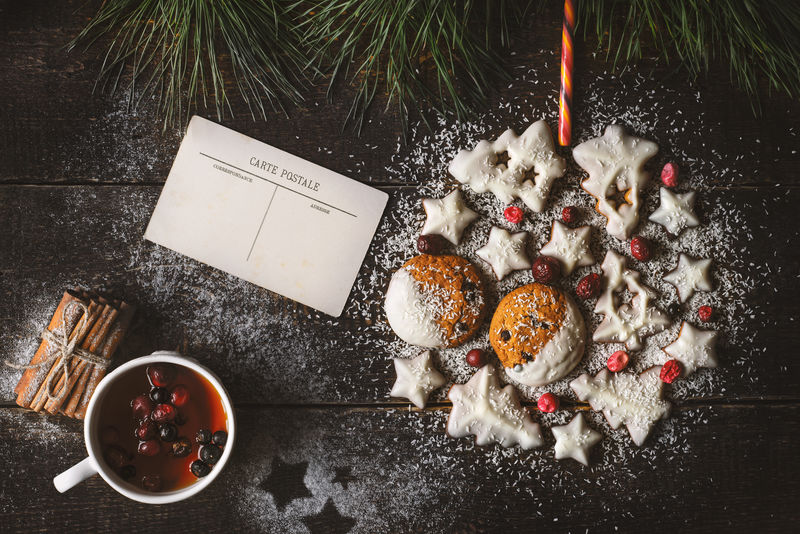 木制背景曲奇制作的圣诞球有明信片和浆果茶