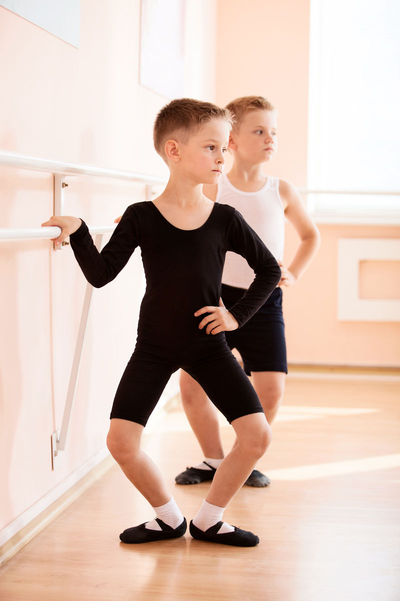 在芭蕾舞班上在扶手杆上工作的年轻男孩