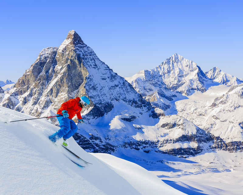 在高山上用新鲜的粉末雪滑雪的滑雪者锡