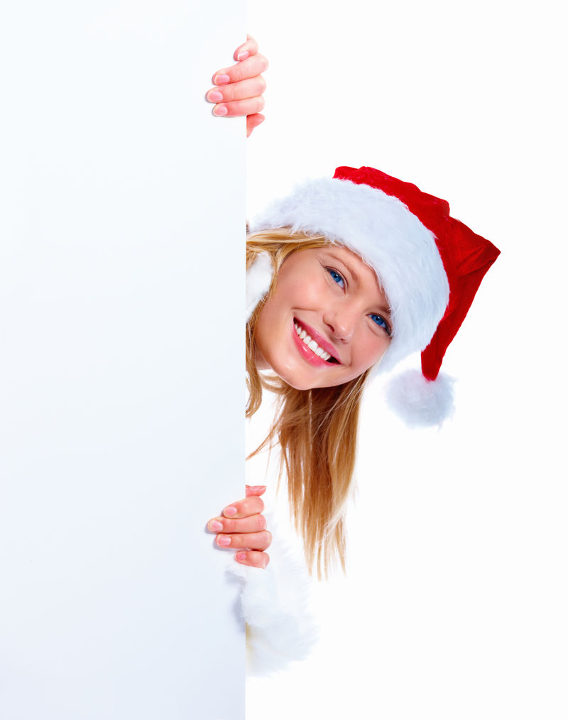 微笑的圣诞女孩躲在标语牌后面偷看-画室的肖像是白色的