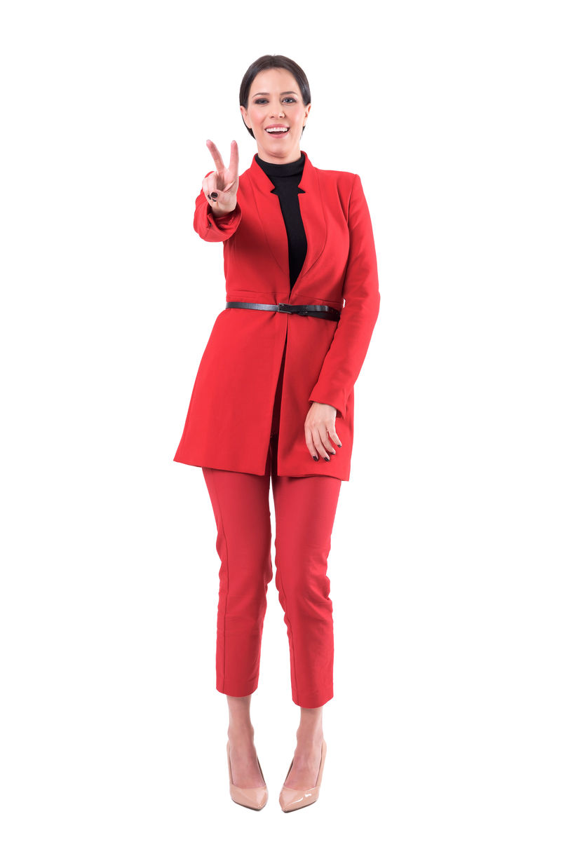 快乐迷人的商务女性穿着优雅的红色西装显示两个手指胜利或和平的手势全身隔离在白色背景上
