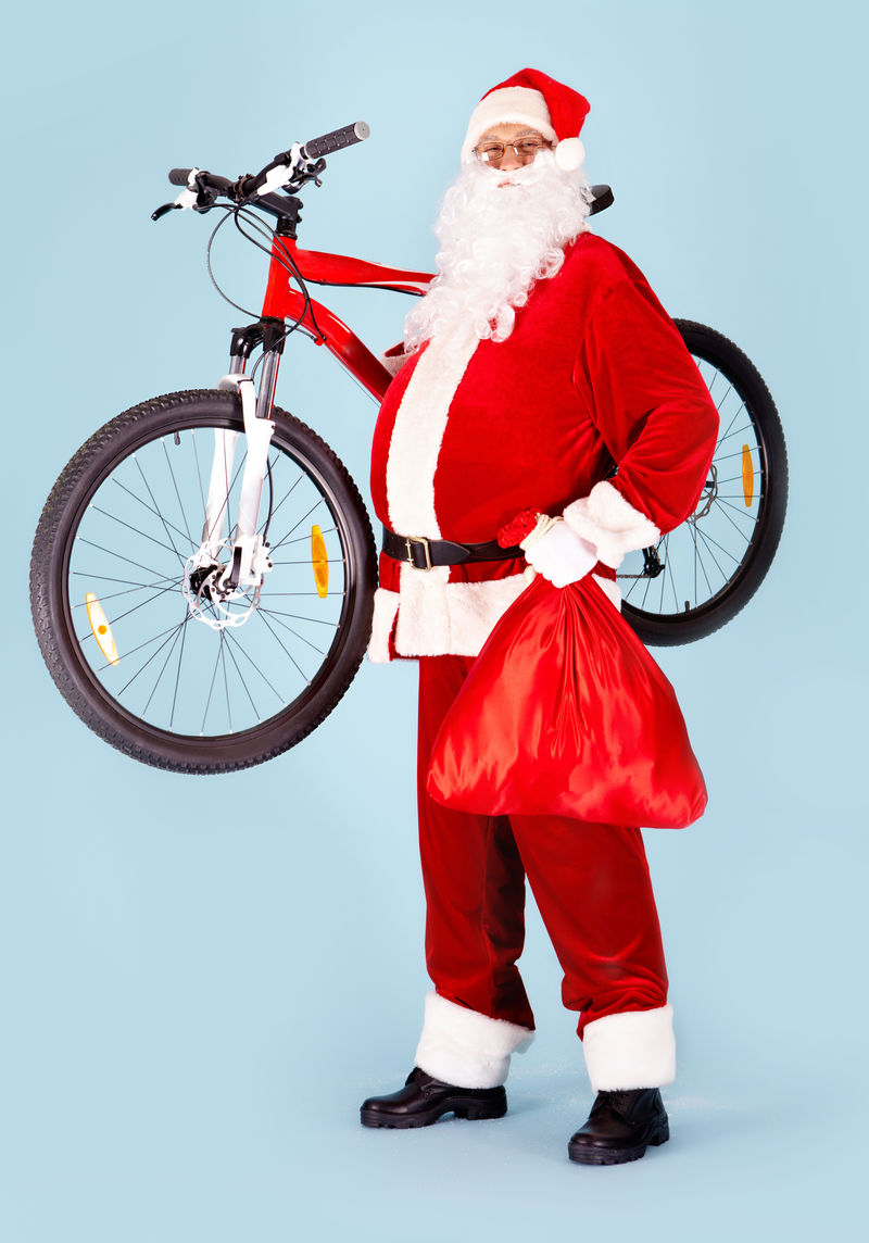 快乐圣诞老人带着红色袋子和自行车看相机的照片