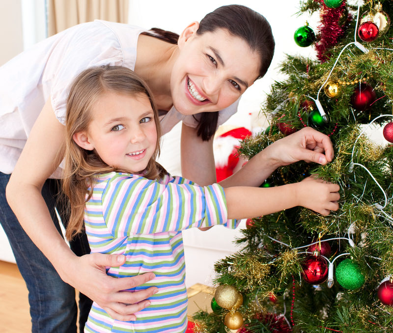 快乐的母亲和女儿装饰圣诞树