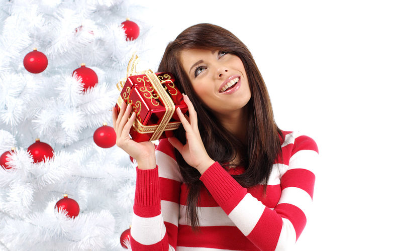 穿着红色圣诞装的微笑可爱的女孩拿着一个大礼盒-竖起大拇指的姿势孤立在灰色的背景上