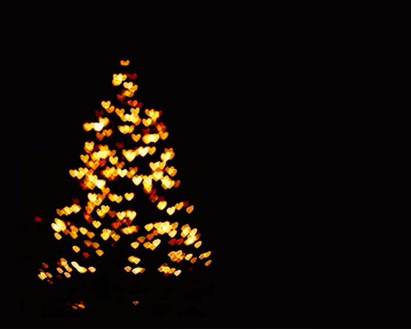 在黑暗的夜晚-模糊的圣诞树的轮廓被照亮-并用金色的精灵灯装饰-创造出抽象的博基圆和发光的圆点-用于节日卡片的图像和文本复制空间