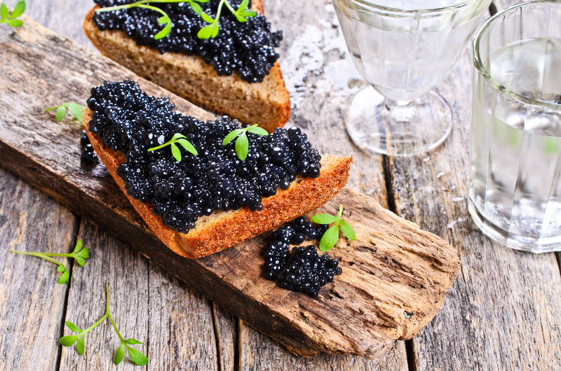 黑色鱼子酱在一块黑色面包上在木制表面上以质朴的风格