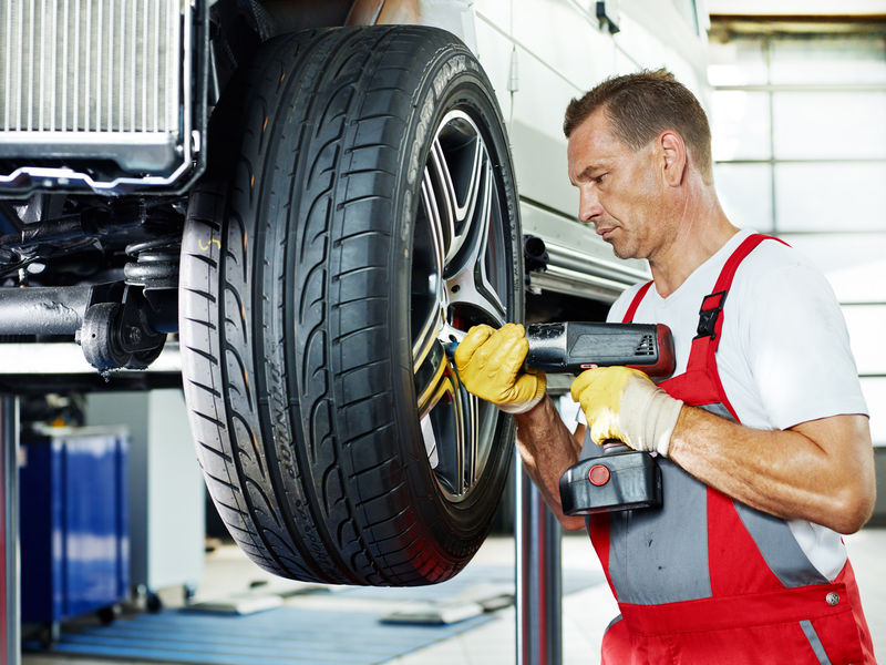 汽车修理工正在用新的铝轮辋更换轮胎
