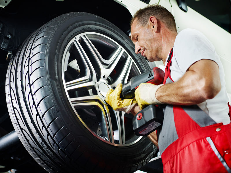汽车修理工正在用新的铝轮辋更换轮胎