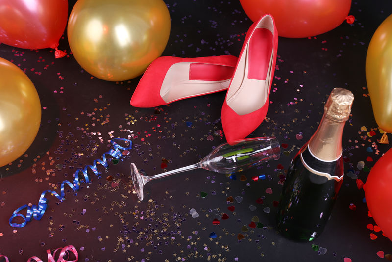 地板上有五彩纸屑香槟和气球的鞋子