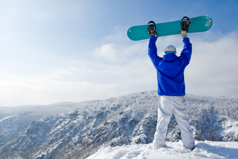 站在山顶的滑雪板运动员的后视图