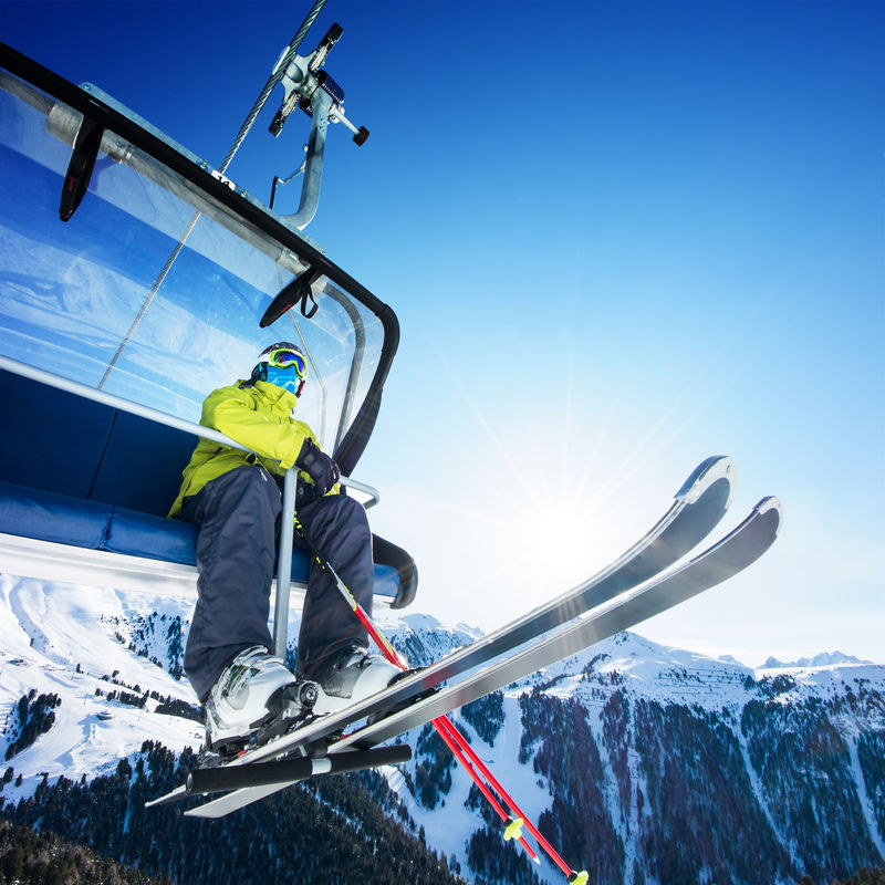 坐在高山滑雪缆车上的滑雪者
