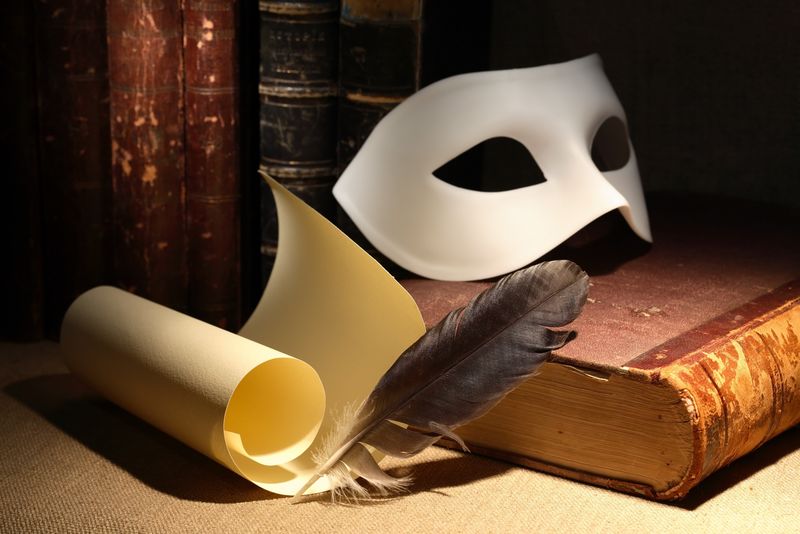 戏剧性的概念-复古的静物生活-带有羽毛笔和卷轴-靠近面具和黑暗背景下的古书