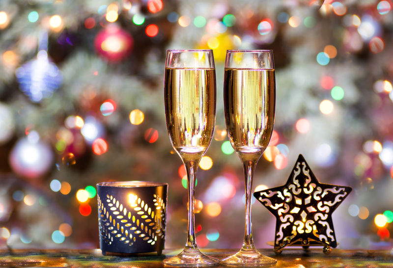 圣诞树背景上的香槟色圣诞眼镜-玩具上装饰着五颜六色的星星形烛台