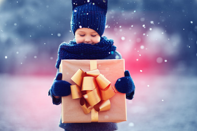 一个可爱的孩子在雪下有一个大礼物盒聚焦礼品盒