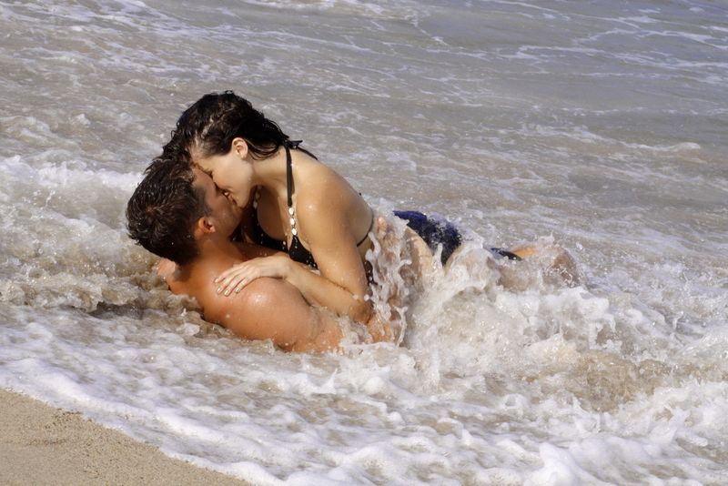 年轻夫妇躺在海浪中接吻