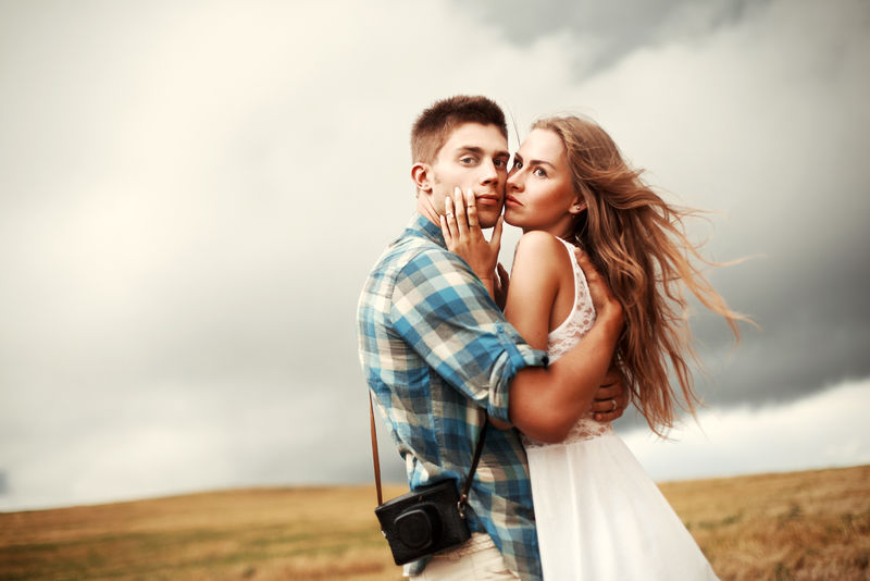 一对相爱的年轻漂亮的情侣在夏日的傍晚一起站在玉米地的乡间-英俊的男人和他的金发女朋友摆造型