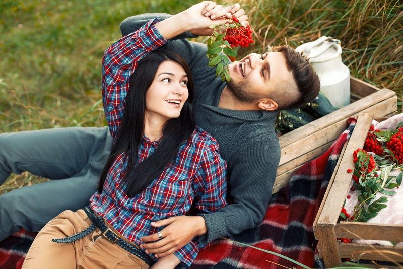 年轻漂亮的时尚情侣相爱在秋天到户外玩-漂亮的深色性感女孩和她英俊的男朋友一起躺在地毯上的草地上