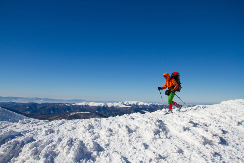 冬天在雪山上徒步旅行背着背包和帐篷