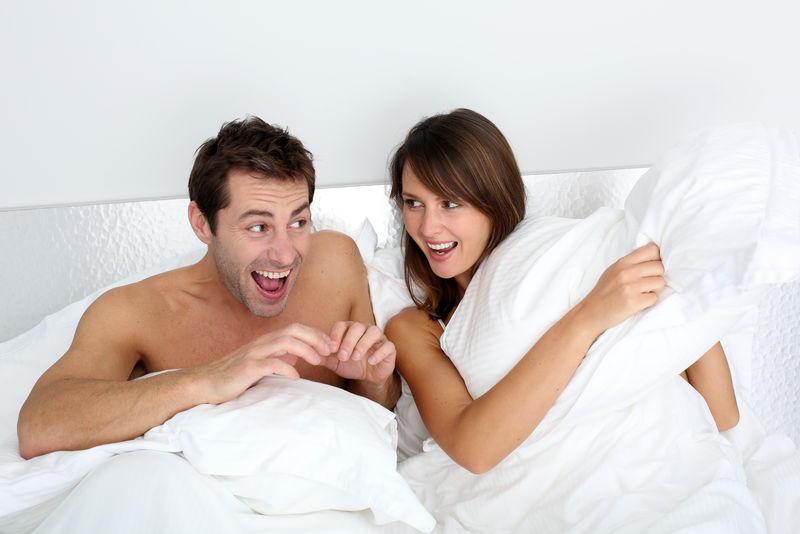 在床上玩枕头的夫妇