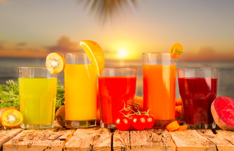 新鲜果汁-水果和蔬菜在日落背景的木桌上混合
